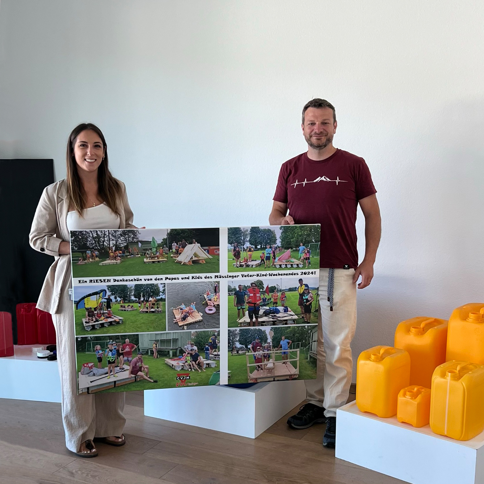 Spendenübergabe von Kanistern mit zwei Vertretern die ein Dankesschild in der Hand halten